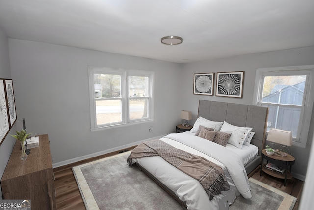 bedroom with multiple windows and dark hardwood / wood-style flooring