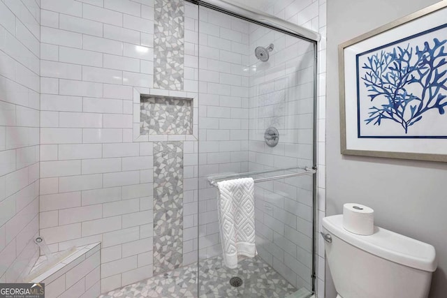 bathroom featuring toilet and a shower with shower door