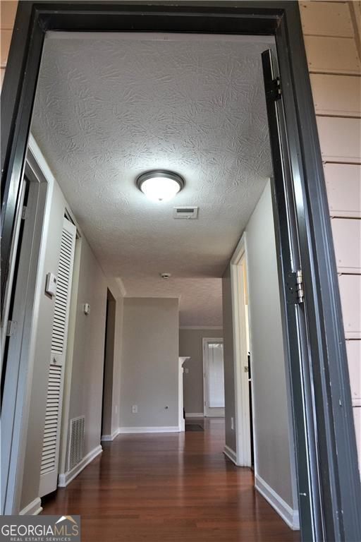 corridor featuring dark hardwood / wood-style flooring and a textured ceiling