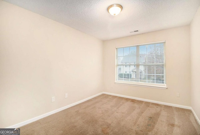 carpeted spare room with a textured ceiling