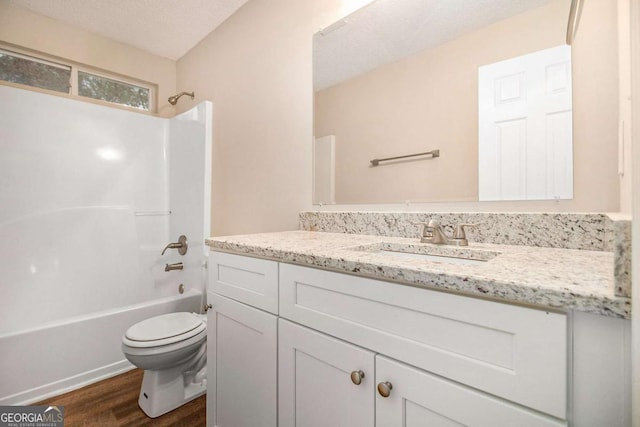 full bathroom with shower / bath combination, vanity, a textured ceiling, wood-type flooring, and toilet