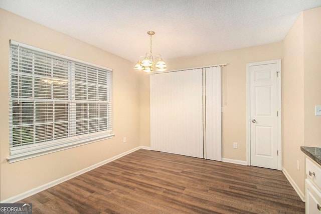 unfurnished bedroom with dark hardwood / wood-style flooring, a chandelier, and a textured ceiling