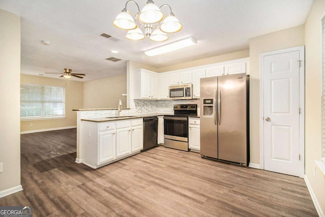 kitchen with decorative light fixtures, light wood-type flooring, white cabinetry, and appliances with stainless steel finishes