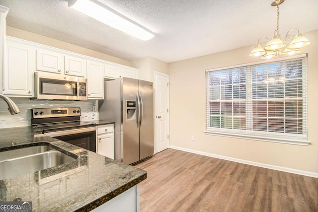 kitchen with white cabinetry, sink, backsplash, appliances with stainless steel finishes, and light wood-type flooring