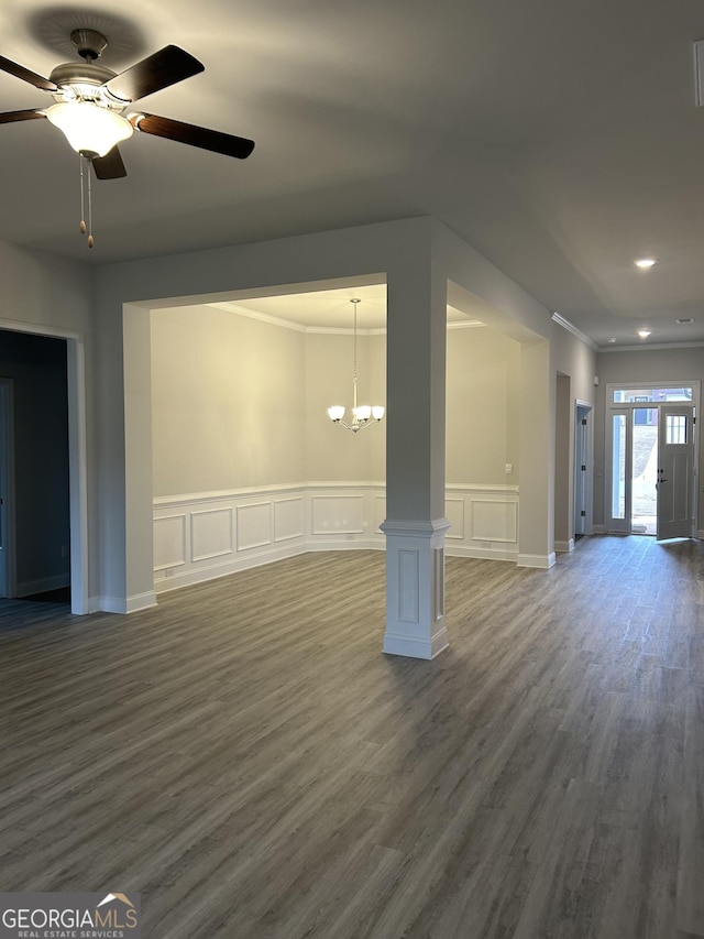 unfurnished living room featuring ornamental molding, ceiling fan with notable chandelier, decorative columns, and dark wood-type flooring