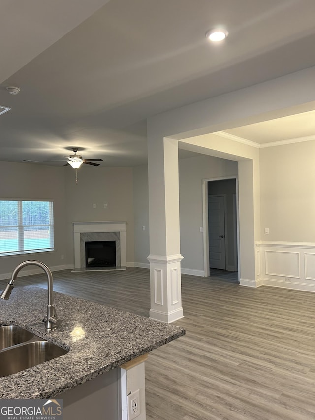 kitchen with ornamental molding, sink, hardwood / wood-style flooring, dark stone countertops, and a fireplace