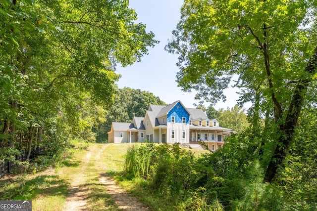 back of house featuring dirt driveway