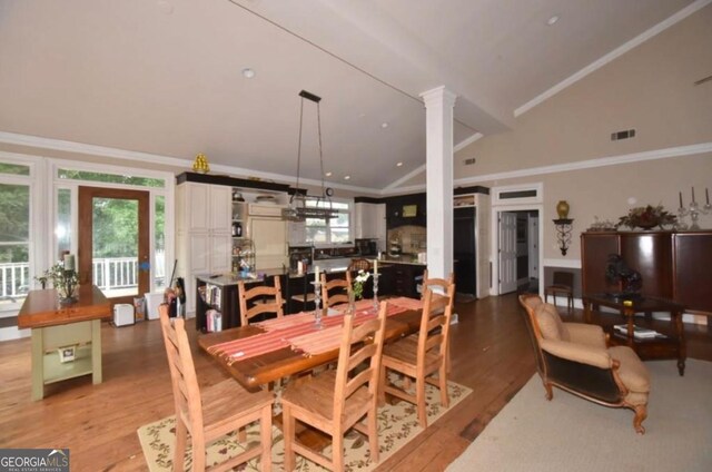 dining area featuring visible vents, ornate columns, light wood finished floors, lofted ceiling, and ornamental molding