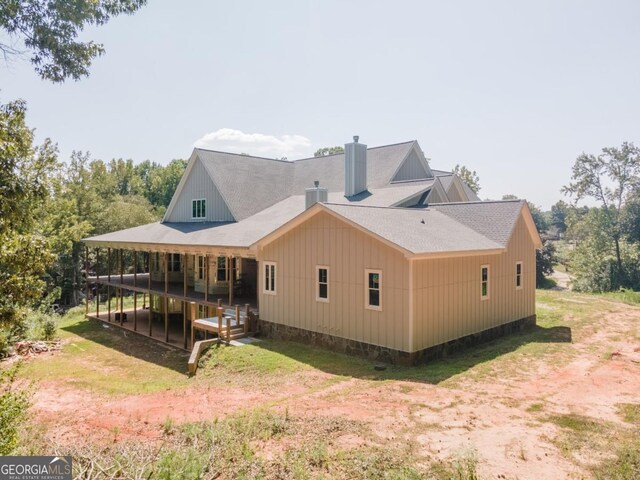 back of house featuring roof with shingles and a chimney