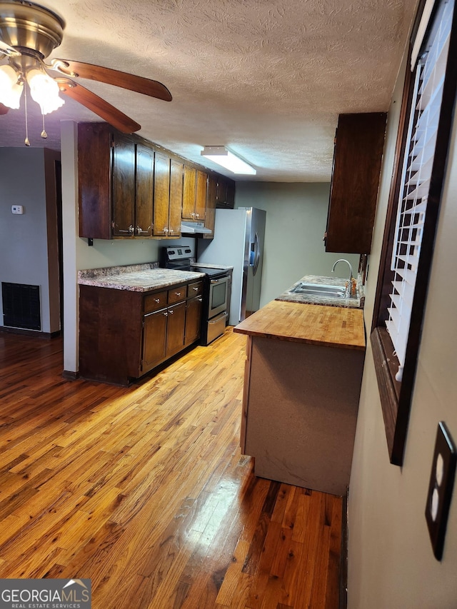 kitchen with ceiling fan, sink, light hardwood / wood-style floors, a textured ceiling, and appliances with stainless steel finishes