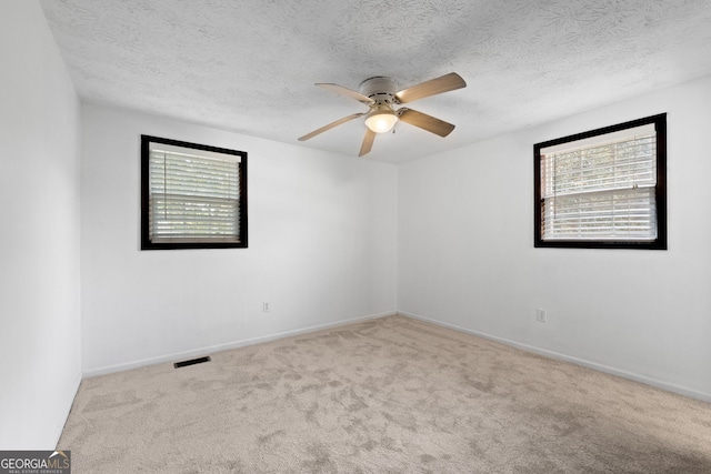 empty room featuring visible vents, carpet floors, plenty of natural light, and ceiling fan