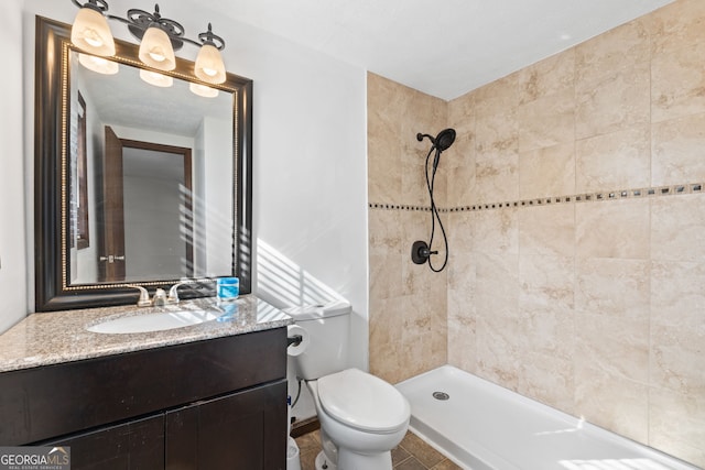 full bath featuring vanity, toilet, and tiled shower