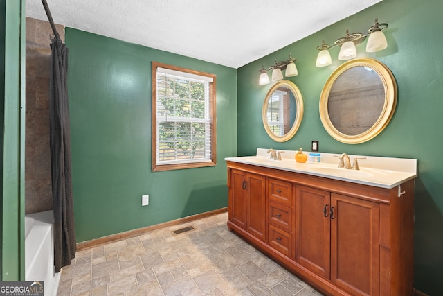 bathroom featuring visible vents, stone finish flooring, baseboards, double vanity, and a sink