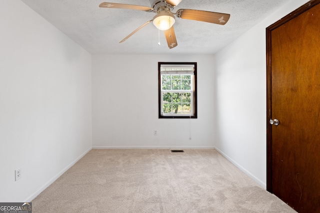 carpeted empty room with ceiling fan, visible vents, baseboards, and a textured ceiling