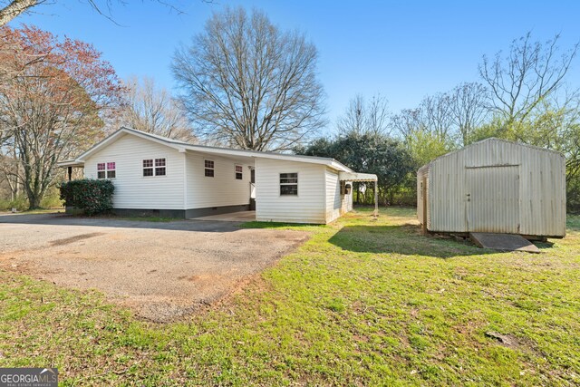 view of front facade featuring a storage unit, driveway, an outdoor structure, crawl space, and a carport