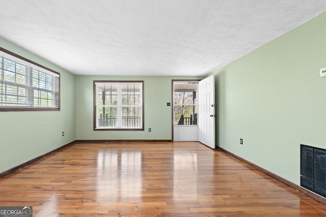 interior space featuring visible vents, baseboards, a textured ceiling, and wood finished floors