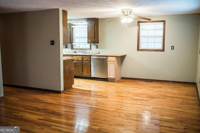 kitchen with stainless steel dishwasher, light hardwood / wood-style floors, and a textured ceiling