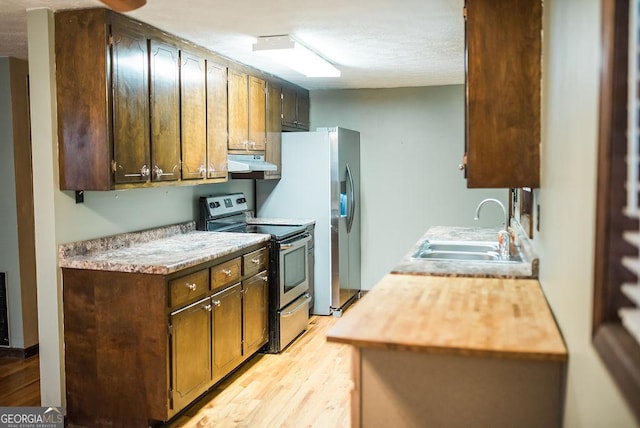 kitchen featuring sink, stainless steel appliances, a textured ceiling, and light hardwood / wood-style floors