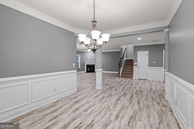 unfurnished living room with a notable chandelier, light wood-type flooring, and crown molding