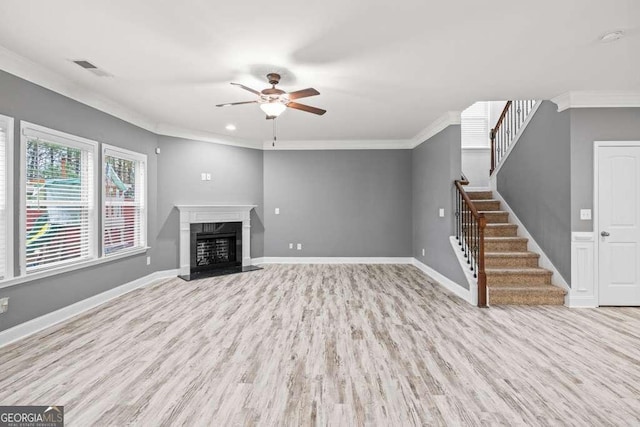 unfurnished living room featuring crown molding, a fireplace, ceiling fan, and light wood-type flooring