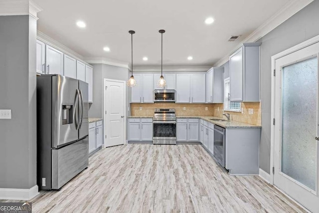 kitchen featuring appliances with stainless steel finishes, light stone counters, ornamental molding, sink, and light hardwood / wood-style flooring