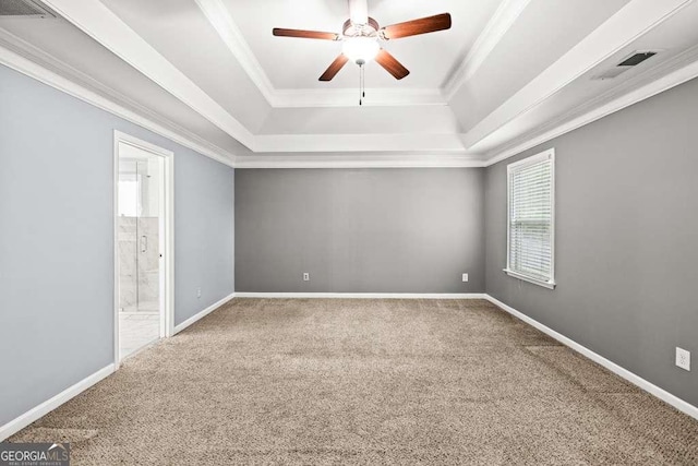 carpeted spare room featuring a raised ceiling, ceiling fan, and ornamental molding