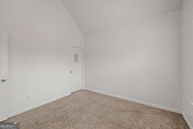 carpeted spare room featuring vaulted ceiling