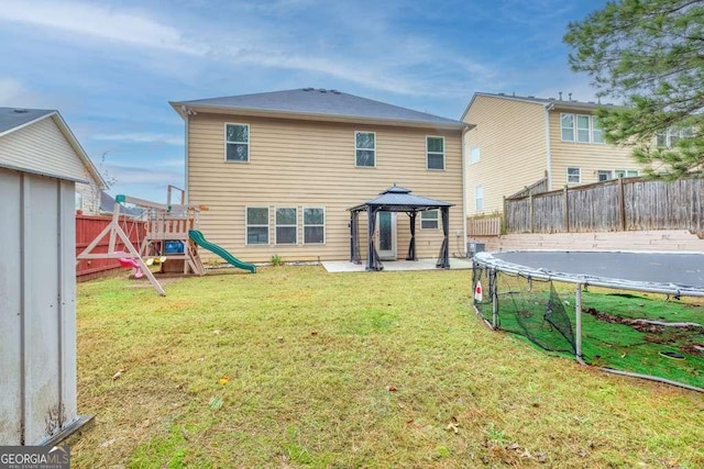 rear view of house featuring a gazebo, a playground, a trampoline, and a yard