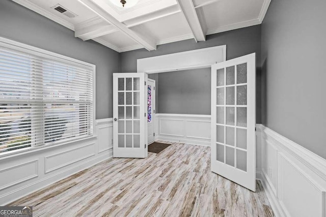 unfurnished room featuring beam ceiling, french doors, coffered ceiling, crown molding, and light wood-type flooring