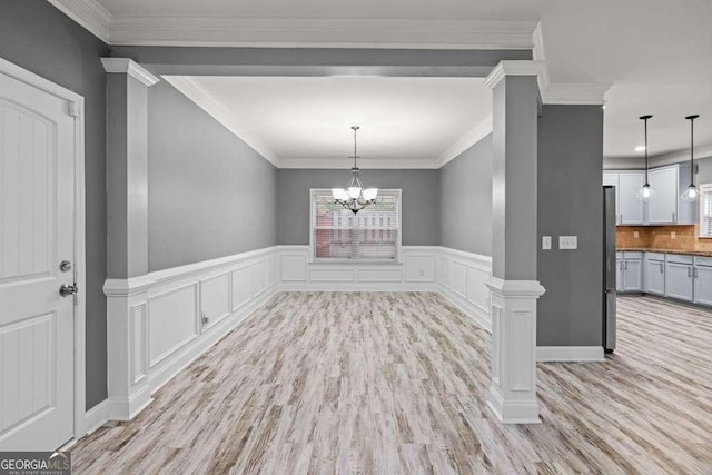 unfurnished dining area featuring light hardwood / wood-style floors, ornate columns, and ornamental molding