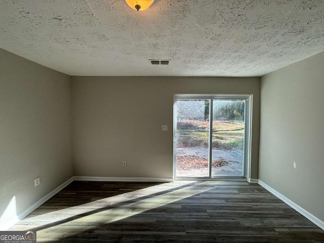 spare room featuring dark wood-type flooring and a textured ceiling