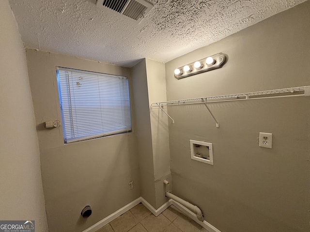 clothes washing area with a textured ceiling, hookup for a washing machine, and tile patterned flooring