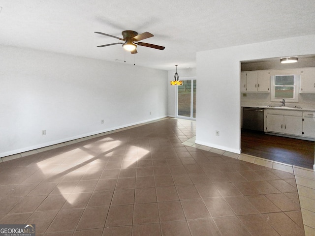 unfurnished living room featuring a textured ceiling, dark tile patterned flooring, ceiling fan, and sink