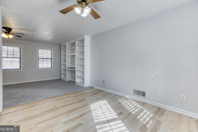 unfurnished living room with ceiling fan, a textured ceiling, and light hardwood / wood-style flooring