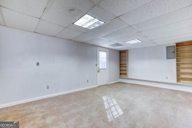 carpeted empty room featuring electric panel and a drop ceiling