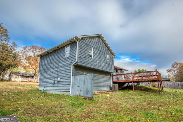 back of property with a deck, cooling unit, and a lawn