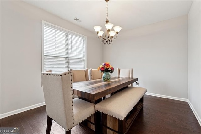 dining space featuring dark hardwood / wood-style floors and an inviting chandelier