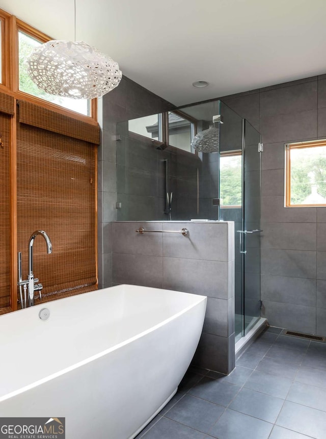 bathroom with tile patterned floors, plus walk in shower, and tile walls