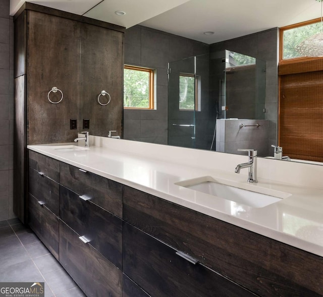 bathroom with a tile shower, vanity, tile patterned floors, and a healthy amount of sunlight