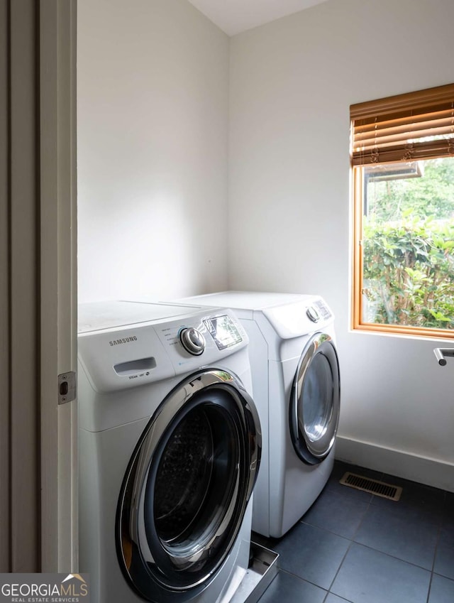 laundry room featuring washer and clothes dryer and dark tile patterned floors