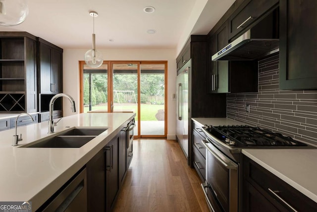 kitchen featuring sink, hardwood / wood-style floors, pendant lighting, extractor fan, and appliances with stainless steel finishes