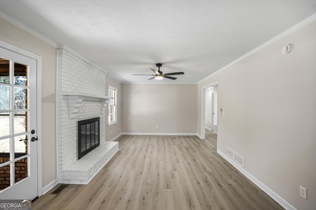 unfurnished living room featuring ceiling fan, a healthy amount of sunlight, light hardwood / wood-style floors, and a brick fireplace