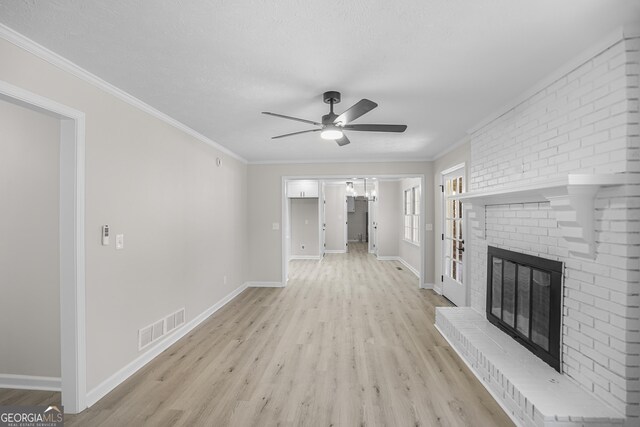 unfurnished living room featuring crown molding, light hardwood / wood-style flooring, ceiling fan with notable chandelier, and a brick fireplace