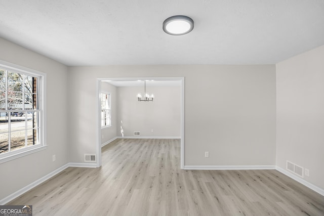 spare room with a chandelier and light hardwood / wood-style flooring