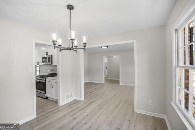 kitchen featuring white cabinetry, stainless steel appliances, light hardwood / wood-style flooring, backsplash, and pendant lighting