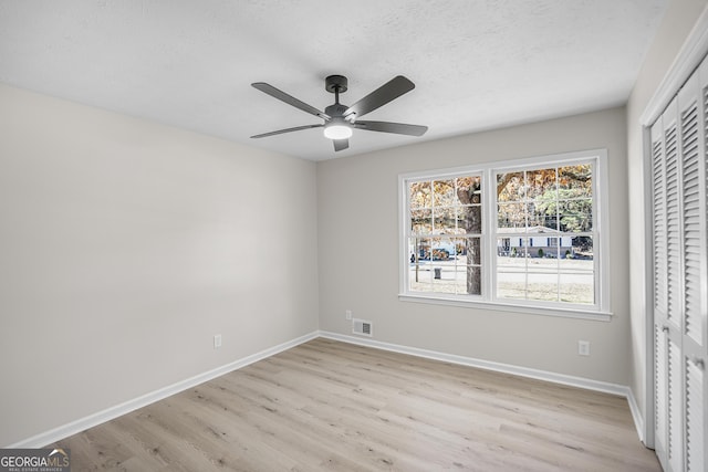 unfurnished bedroom with a textured ceiling, light wood-type flooring, a closet, and ceiling fan