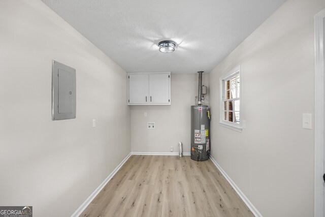 laundry room featuring cabinets, electric panel, gas water heater, light wood-type flooring, and a textured ceiling