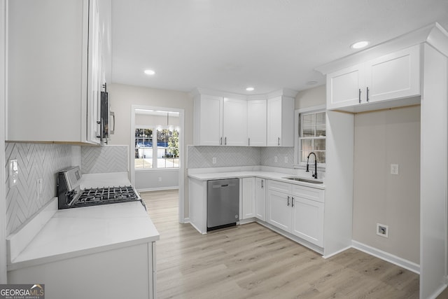 kitchen with sink, stainless steel appliances, tasteful backsplash, white cabinets, and light wood-type flooring