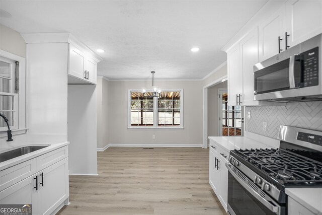 kitchen with sink, stainless steel appliances, light hardwood / wood-style flooring, a chandelier, and white cabinets