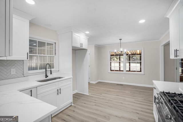 kitchen with decorative backsplash, sink, light hardwood / wood-style flooring, a notable chandelier, and white cabinetry